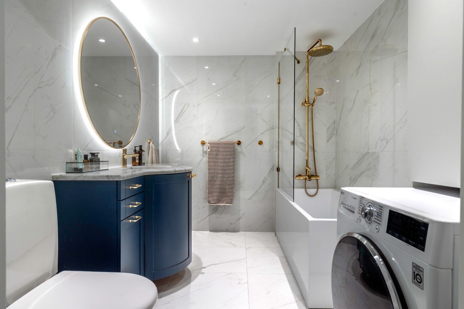 Badet fremstår som moderne og delikat, med et gjennomført og eksklusivt uttrykk. Rommet er helfliset i lyse fliser med marmorinspirert overflate. Det er opplegg for vaskemaskin. Galleribilde