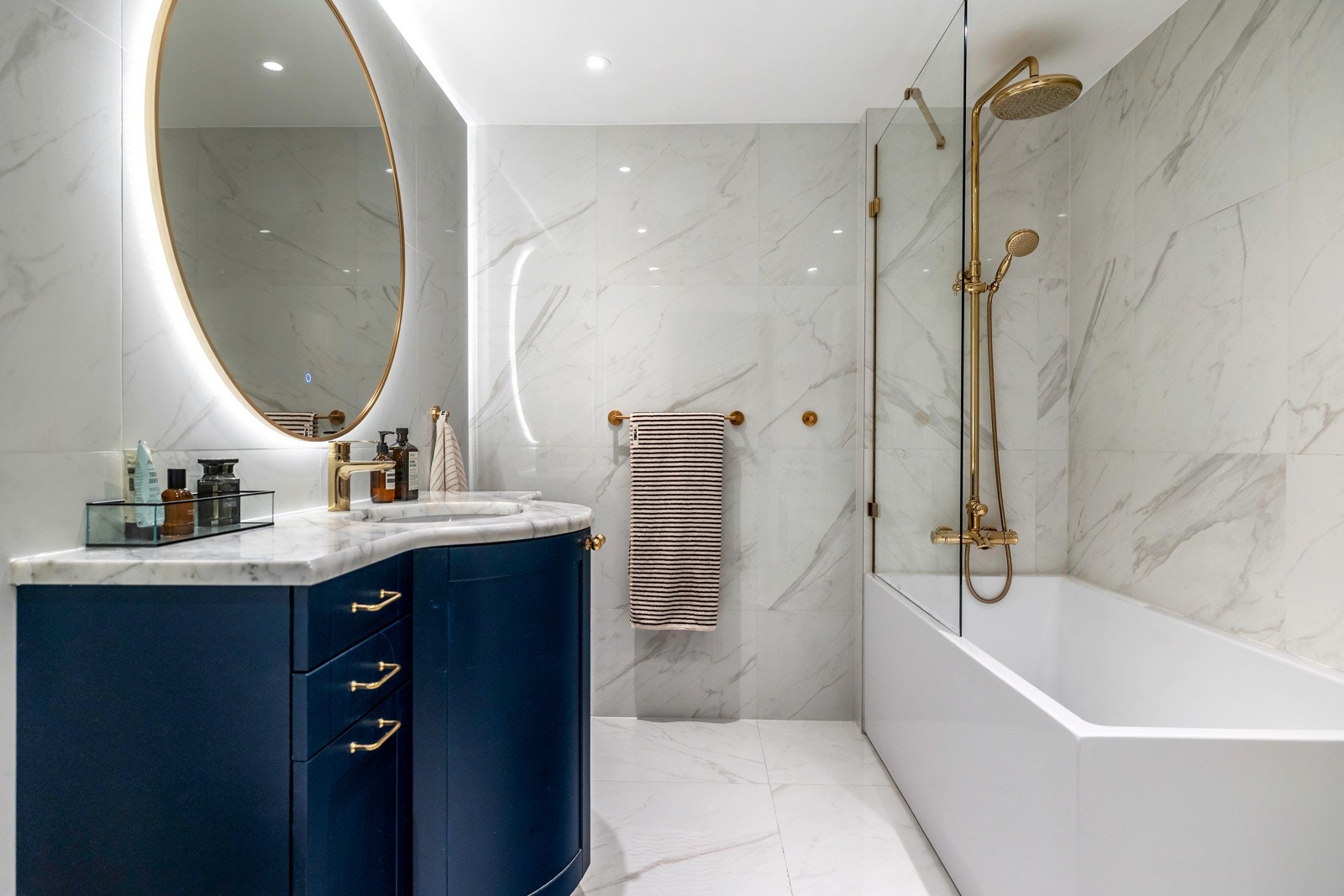 Badet er innredet med vegghengt toalett, stilren servant med innredning fra 2020 og en romslig dusj-/badekarløsning med glassvegg.Servantinnredningen har god oppbevaringsplass og er toppet med benkeplate i stein, kombinert med et elegant speil med integre Galleribilde