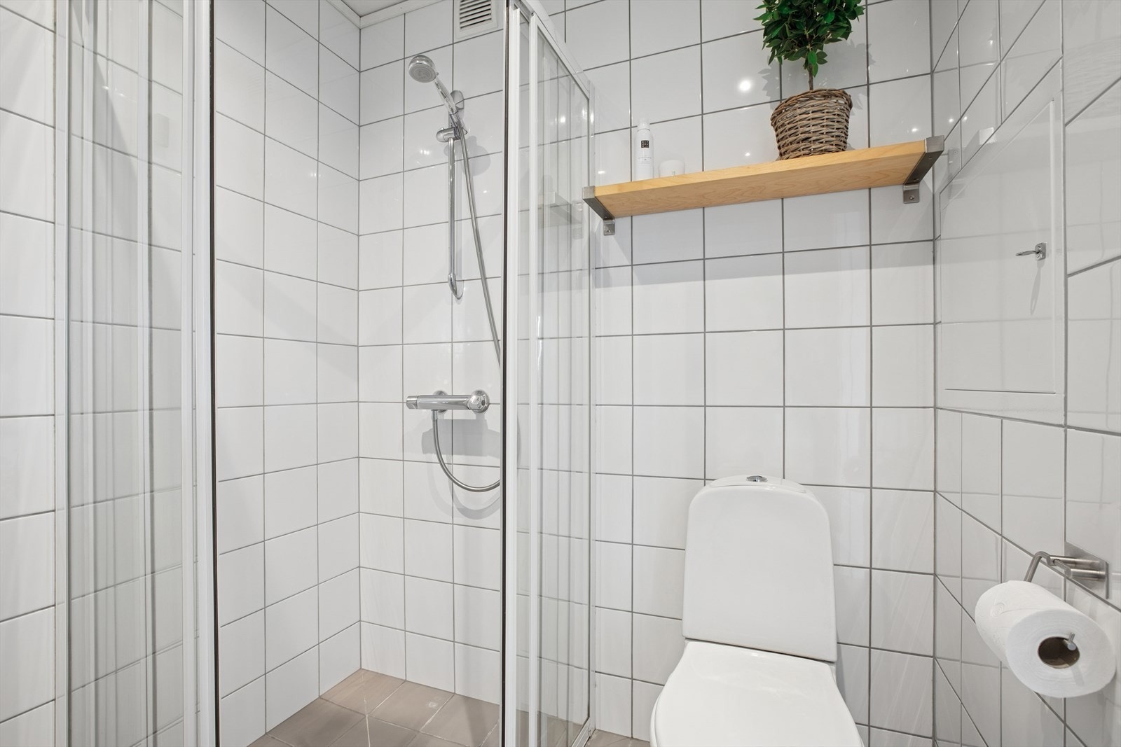 Badet er innredet med dusjnisje med glassdør, toalett, servantinnredning og opplegg for vaskemaskin. Galleribilde