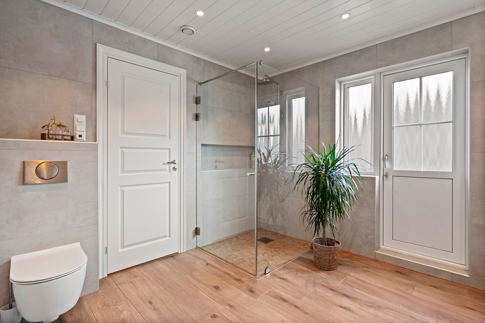 Lekker flislagt bad med varmekabler. Dusjhjørne, vegghengt toalett, baderomsinnredning med skuffer, servant og speil med belysning, samt skapplass. Spotter i tak. Galleribilde