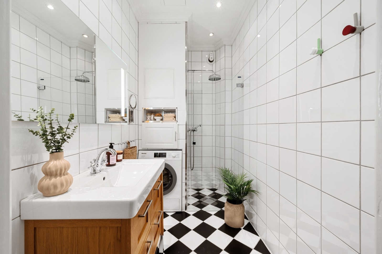 Badete er helfliset og er på ca. 3,8 kvm, med hvite veggfliser og et karakteristisk sjakkrutet gulv som gir rommet et klassisk uttrykk Galleribilde