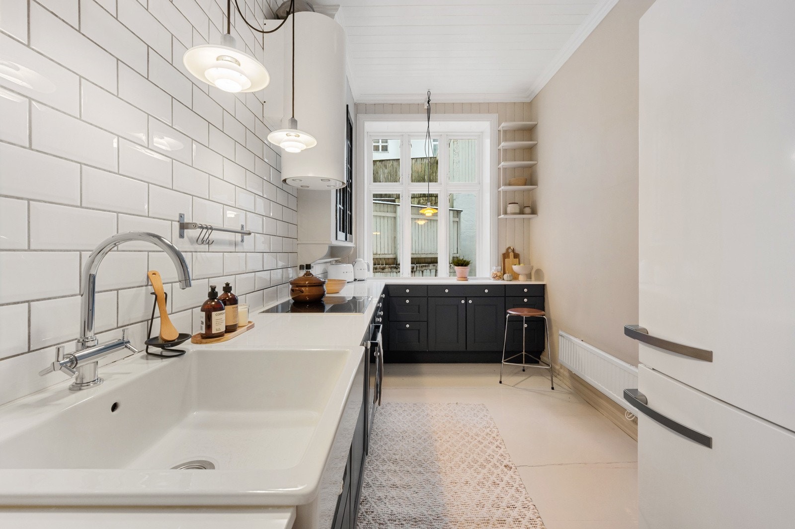 Kjøkkeninnredningen fremstår tidløs med mørke profilerte fronter i pen kontrast mot lys benkeplate i kompositt. Galleribilde