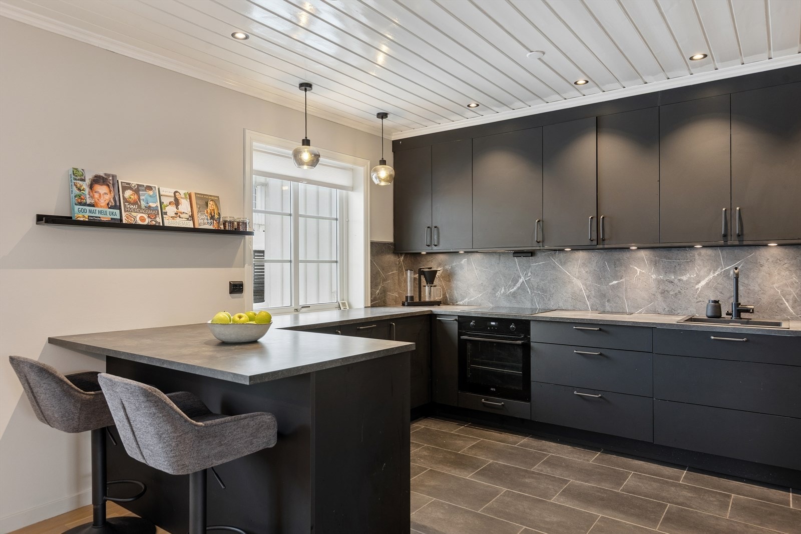 Smakfullt kjøkken (2021) som fremstår moderne og funksjonelt med sorte, stilrene fronter og rikelig med benkeplass. Galleribilde