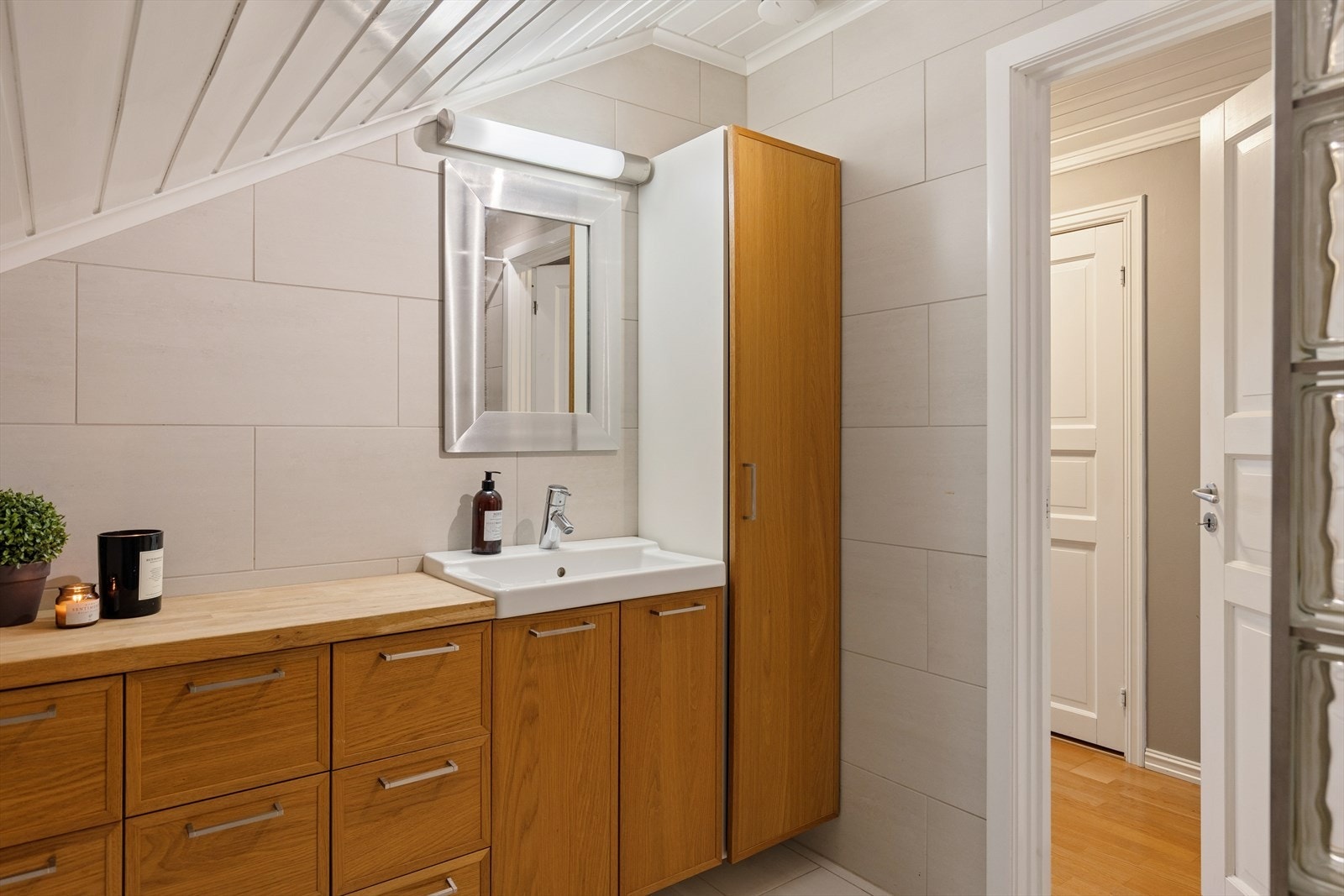 Innbydende helfliset bad med varme i gulv. Rommet har dusjnisje vegg av glassbyggerstein. Innredning med servant. Ventil i himling. Spalt for tilluft ved dør. Galleribilde