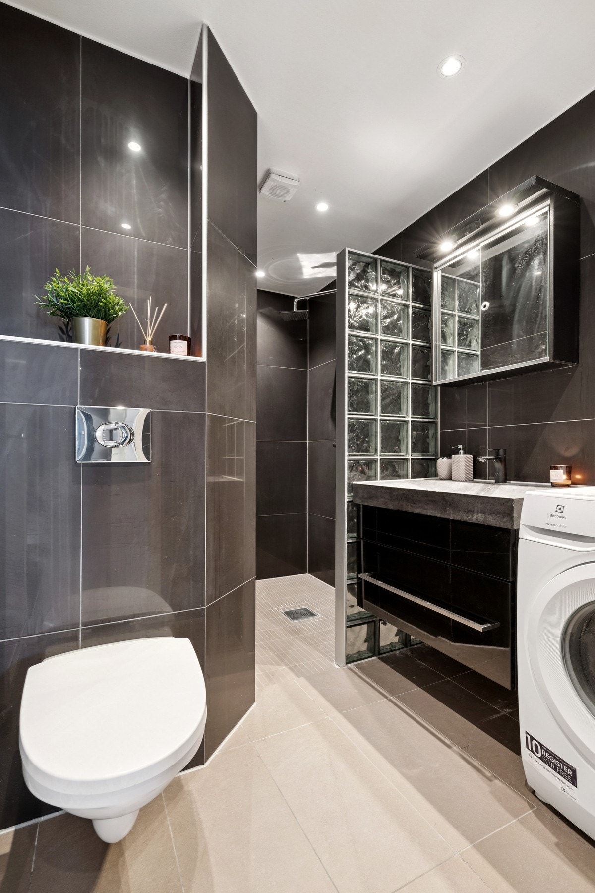 Rommet er innredet med servantinnredning med heldekkende servanttopp, speilskap med integrert belysning, vegghengt toalett, dusjnisje og opplegg for vaskemaskin. Galleribilde