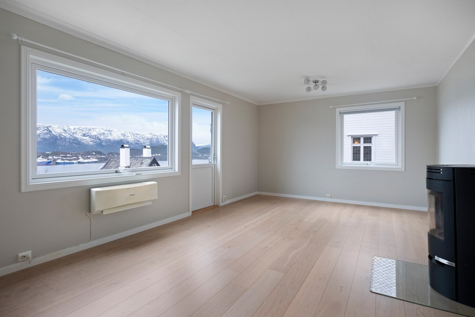 Stor og romslig stue med vedovn og utgang til balkong. Galleribilde