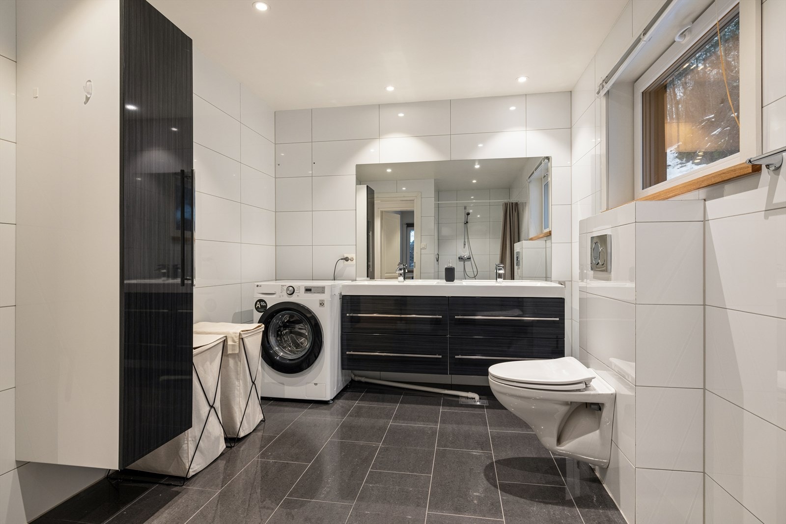 Flislagt bad med dusjnisje, vegghengt toalett og dobbel servant med innredning. Galleribilde