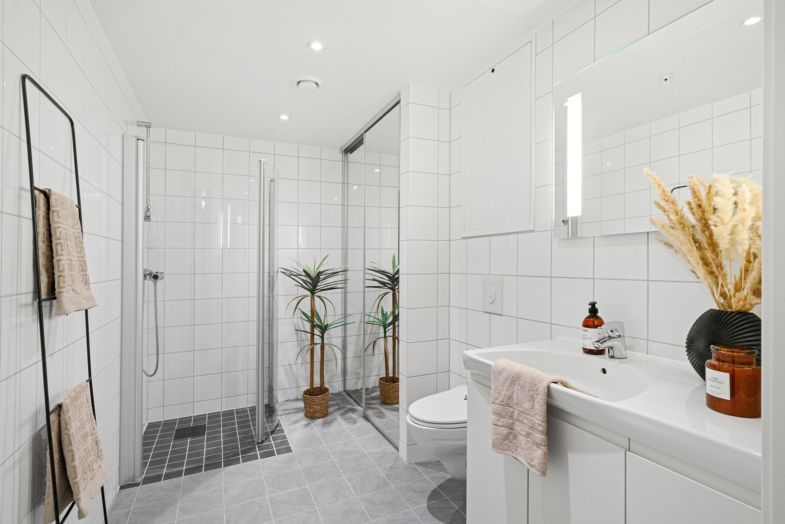 Pent helfliset bad med varme i gulv, vegghengt toalett, dusjhjørne og spotter i tak Galleribilde