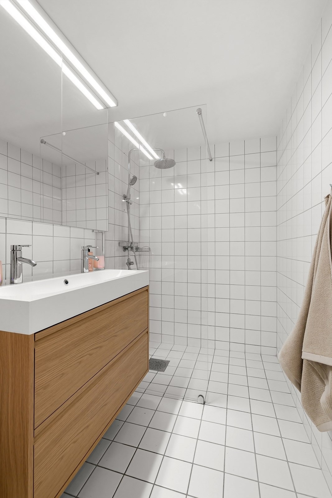 Badet er utstyrt med vegghengt toalett og dusjhjørne med glassvegg i herdet glass og dusjsett med rainshower Galleribilde