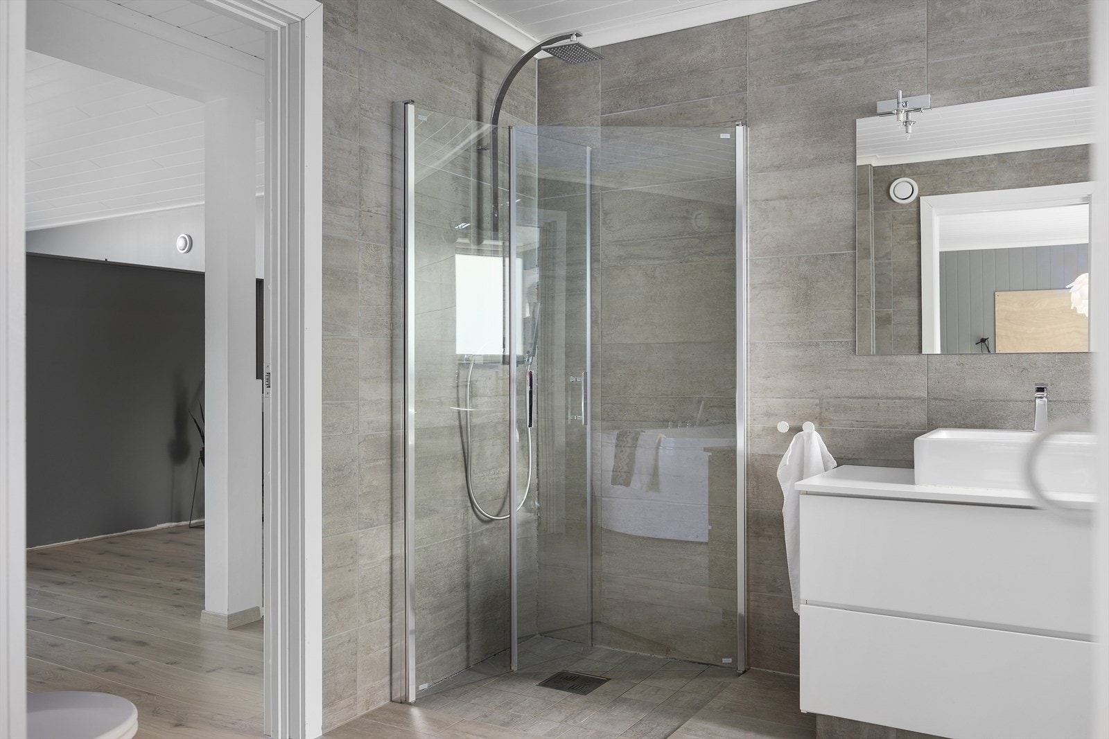 Bad i 2.etasje som fremstår moderne med høy standard. Badet er utstyrt med vegghengt toalett, dusj, stilren baderomsinnredning og badekar som gjør det avslappende og familievennlig. Galleribilde