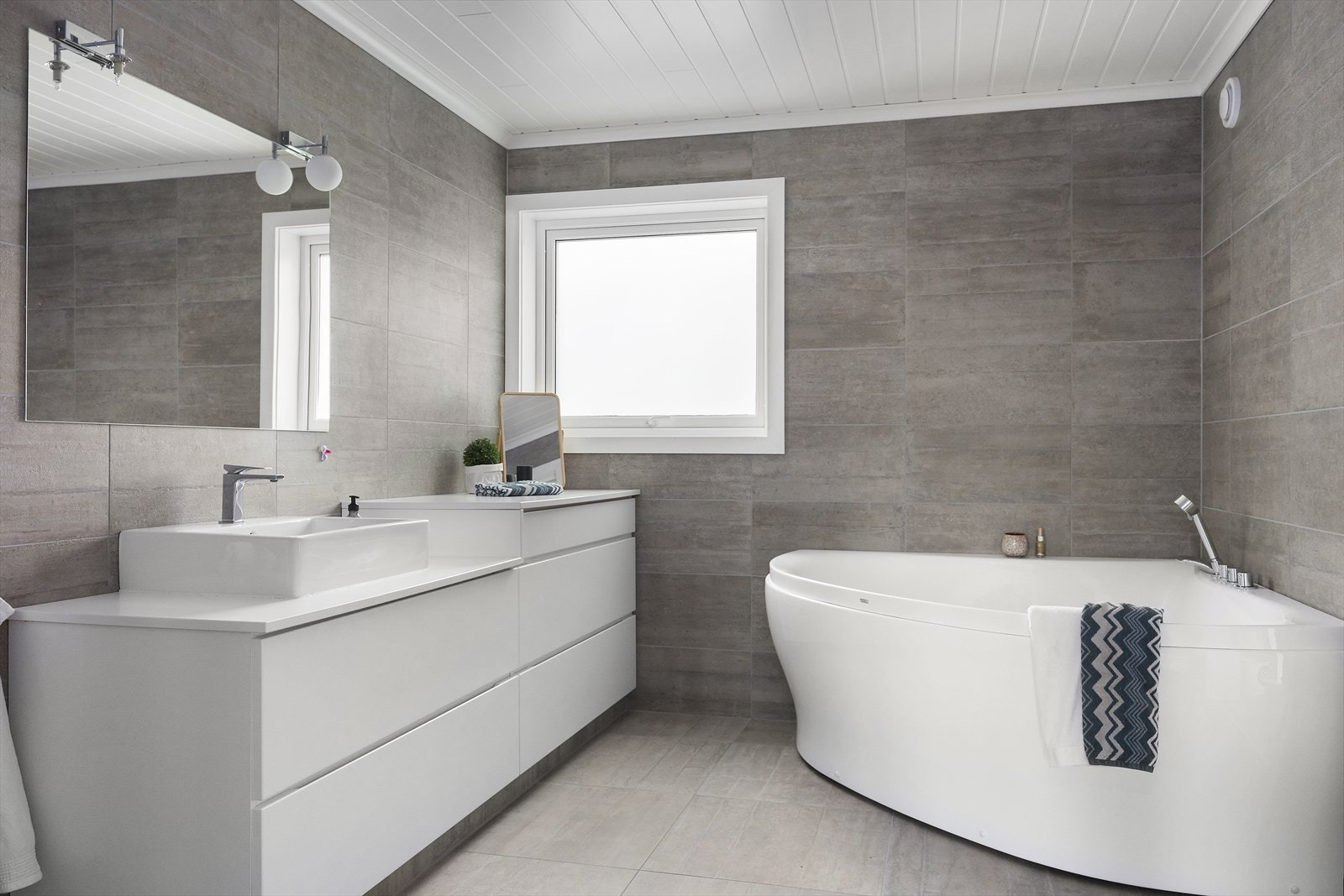 Bad i 2.etasje som fremstår moderne med høy standard. Badet er utstyrt med vegghengt toalett, dusj, stilren baderomsinnredning og badekar som gjør det avslappende og familievennlig. Galleribilde