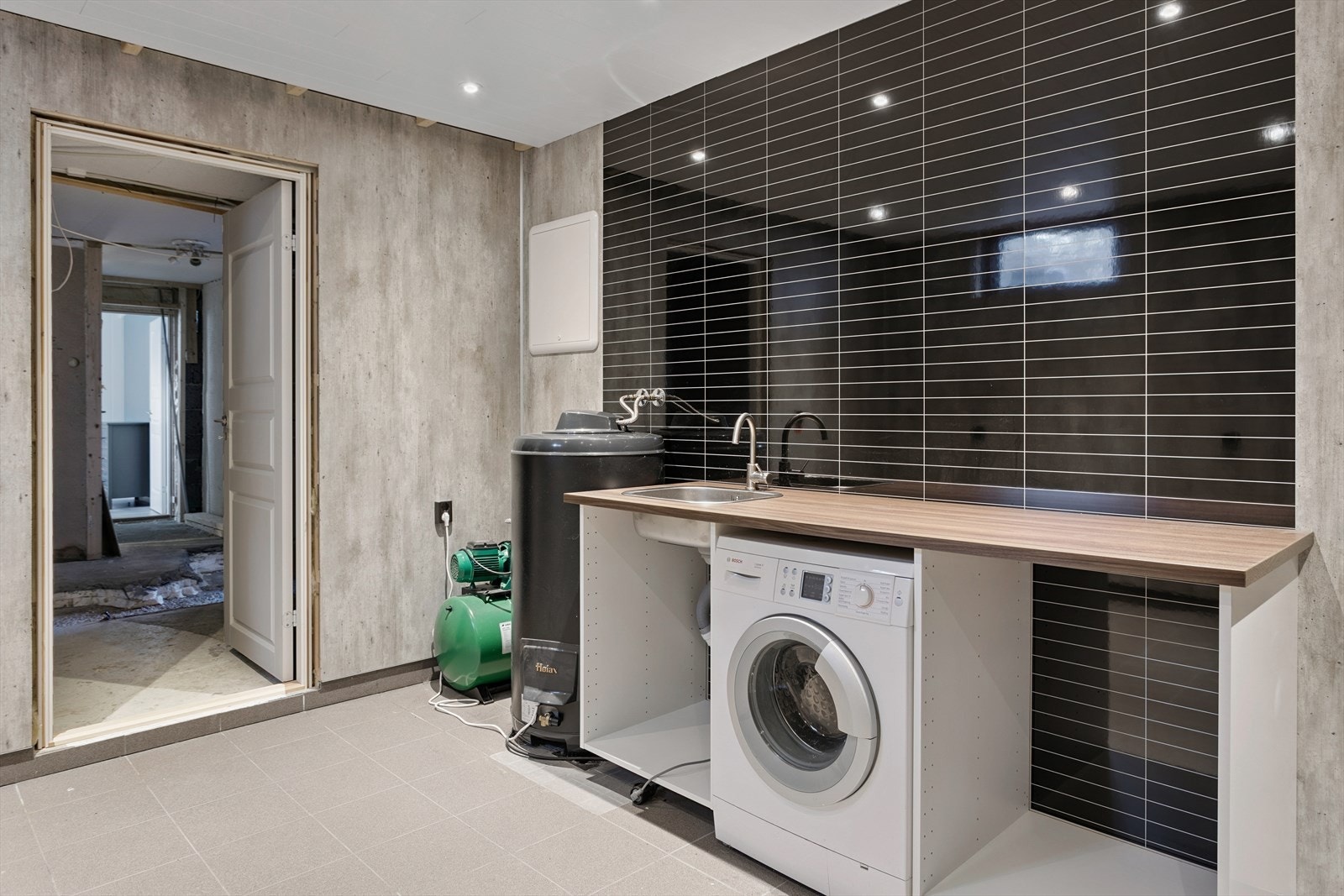 Vaskerom under oppføring har opplegg for vaskemaskin og praktisk arbeidsbenk med utslagsvask. Galleribilde