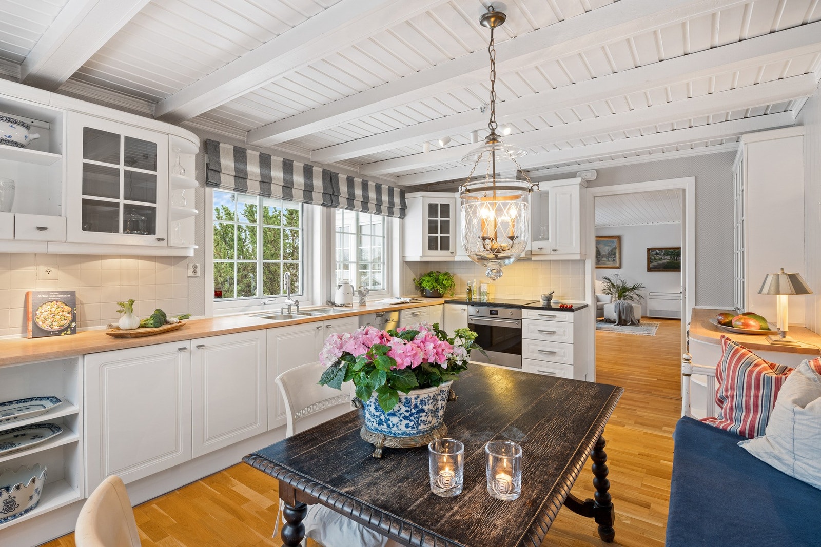 Hyggelig kjøkken med hvit kjøkkeninnredning med profilerte fronter og heltre benkeplate og steinplate. Galleribilde