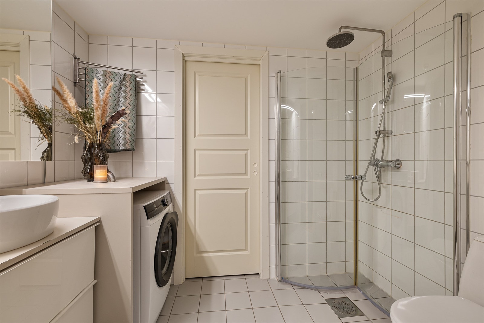 Romslig, flislagt bad med dusjhjørne og inngang til en praktisk innvendig bod. Galleribilde