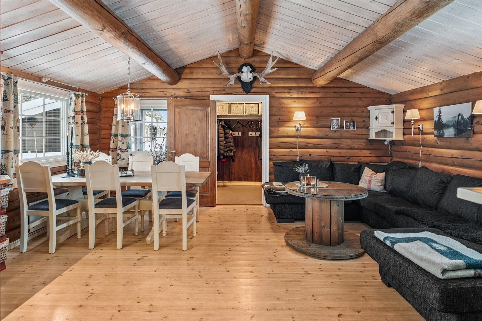 Stuen og spisestuen i en åpen løsning med vegger i laftet tømmer og gulv av furu. Galleribilde