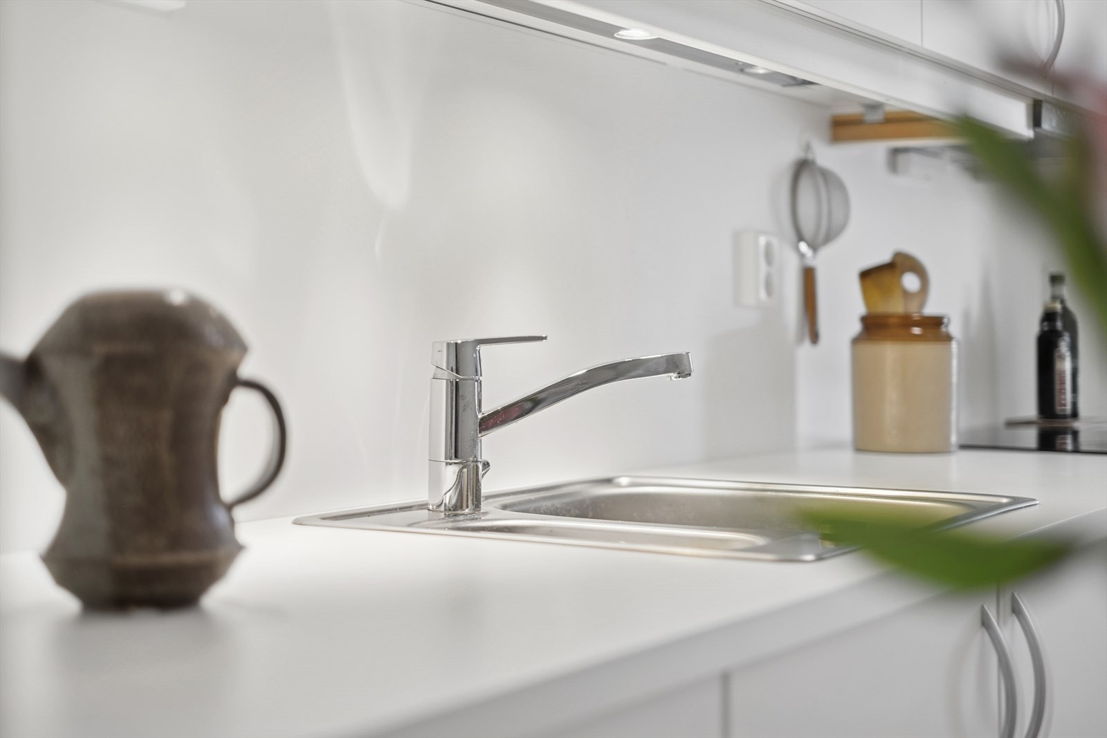 Her er den en pen kjøkkeninnredning utført med hvite, glatte fronter og hvit laminat benkeplate med nedfelt kjøkkenkum. Galleribilde