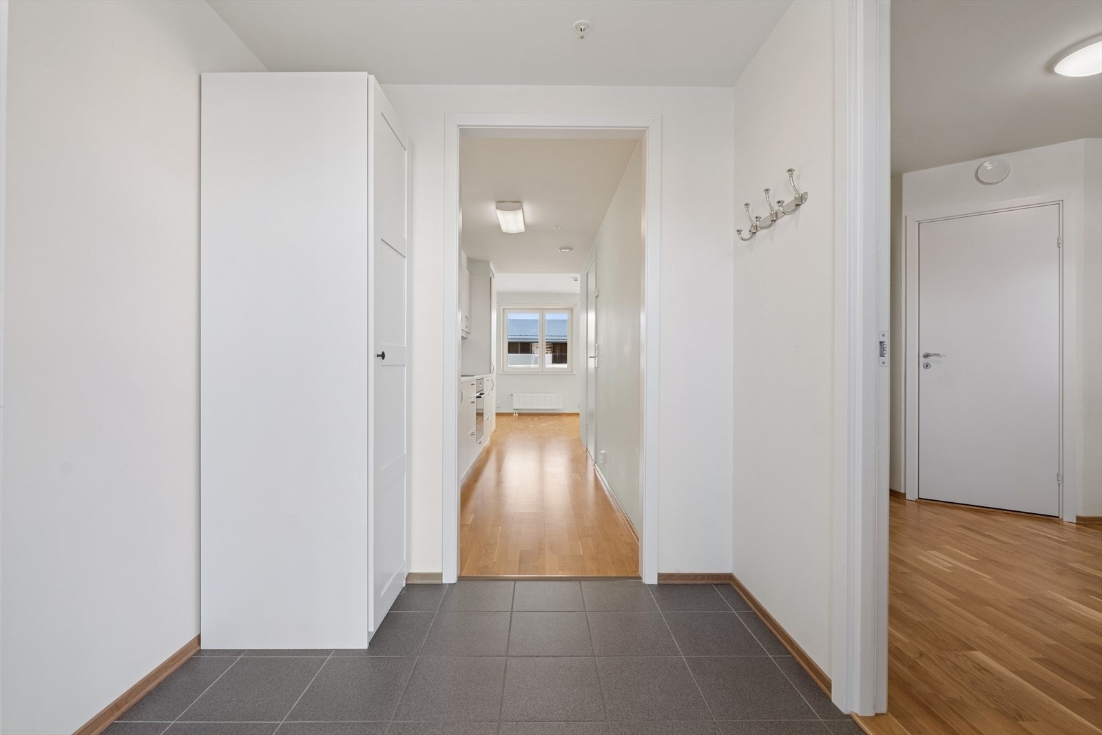 Vel innenfor døren blir du møtt av en romslig og lys entré/gang med fliser på gulvet, og lyse glatte vegger. Galleribilde