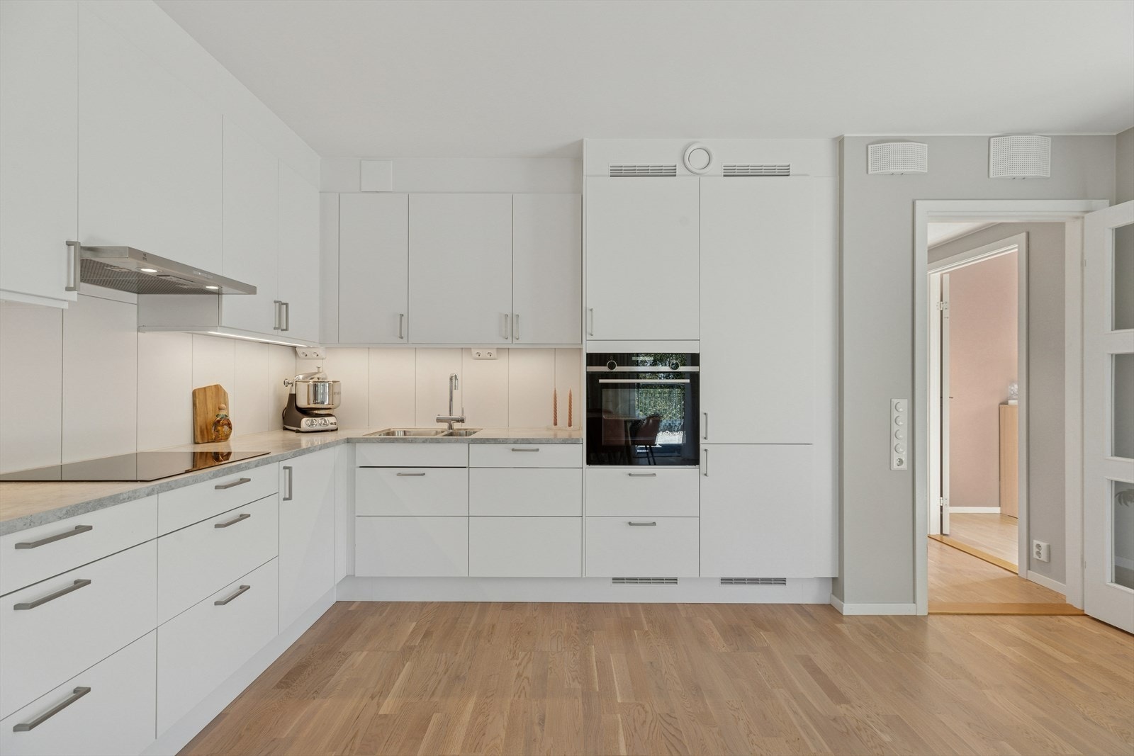 Hvitevarer som induksjonstopp, stekeovn, oppvaskmaskin og kjøle-/fryseskap er integrert i innredningen. Galleribilde