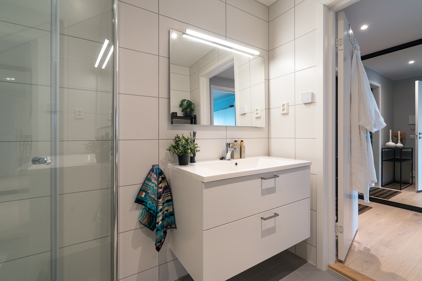 innredningen består av dusjhjørne med innfellbare glassdører, veggfestet toalett, skuffeinnredning med nedfelt servant og stort speil med lys. Foto: Privat. Galleribilde