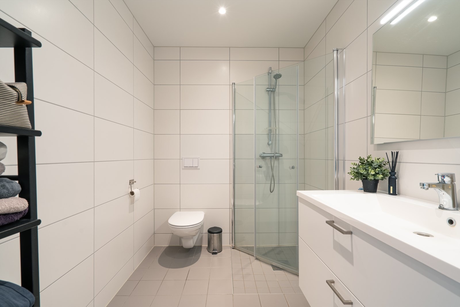 Badet er delikat og tidløst med flislagte overflater i hvitt og grått, varmekabler og downlights. Foto: Privat. Galleribilde