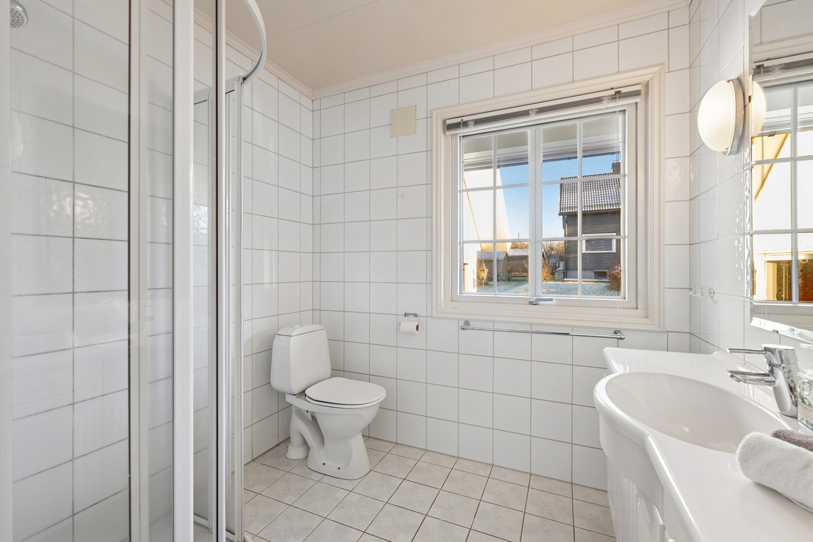 Baderommet er innredet med dusjhjørne, servant med skap og gulvmontert toalett. Galleribilde