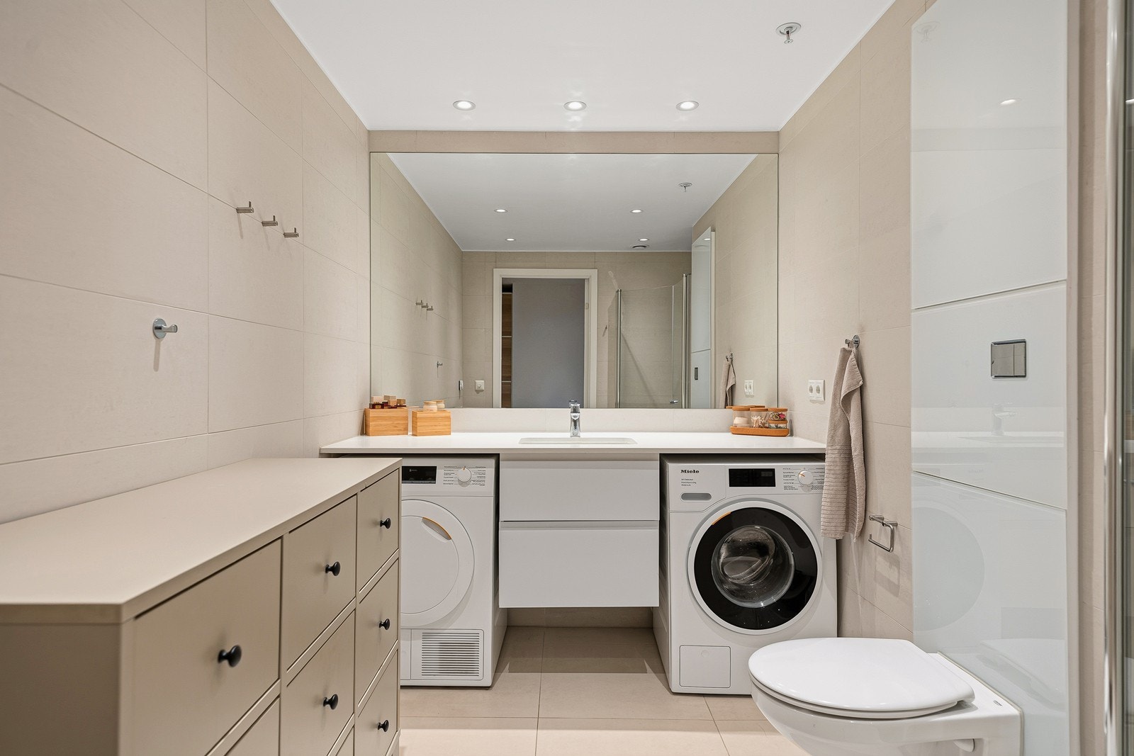 Badet består av baderomsinnredning, toalett, dusjhjørne og opplegg for vask og tørk. Galleribilde