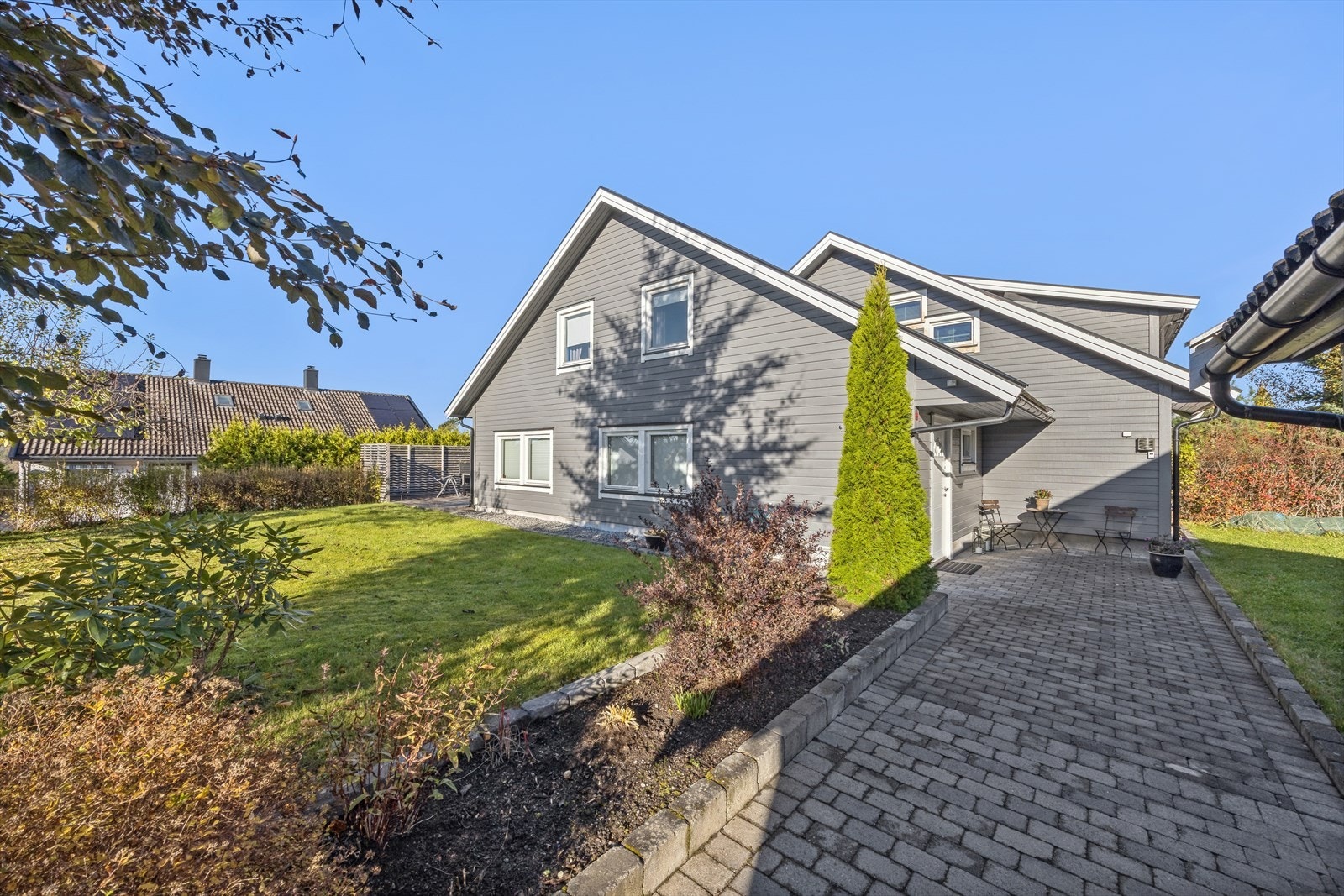 Boligen har en pen og flat tomt med stor plen, frukttrær, prydbusker og steinbelagt gangvei. Galleribilde