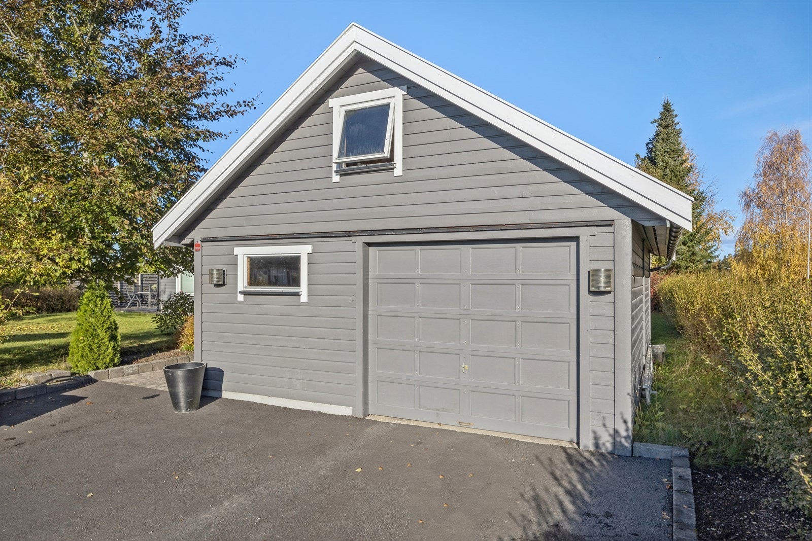 Frittstående garasje fra 2001 med leddport i tre og mekanisk portåpner. Galleribilde