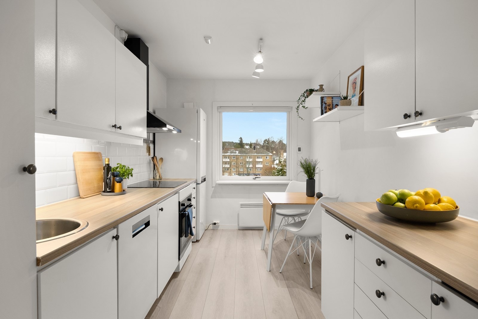 Et lyst og trivelig kjøkken med plass til spiseplass ved vindu og kjøkkeninnredning med glatte fronter. Galleribilde