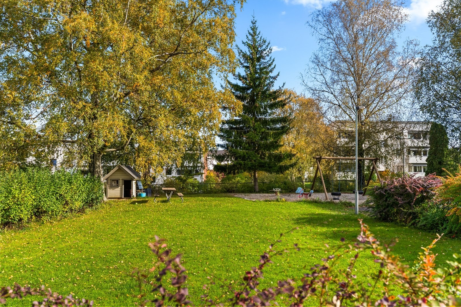 Meget idyllisk felles tomt opparbeidet med asfalterte interne veier, friområde med benker og lekeapparater, gressplen, hekker, ulike prydtrær og busker. Galleribilde
