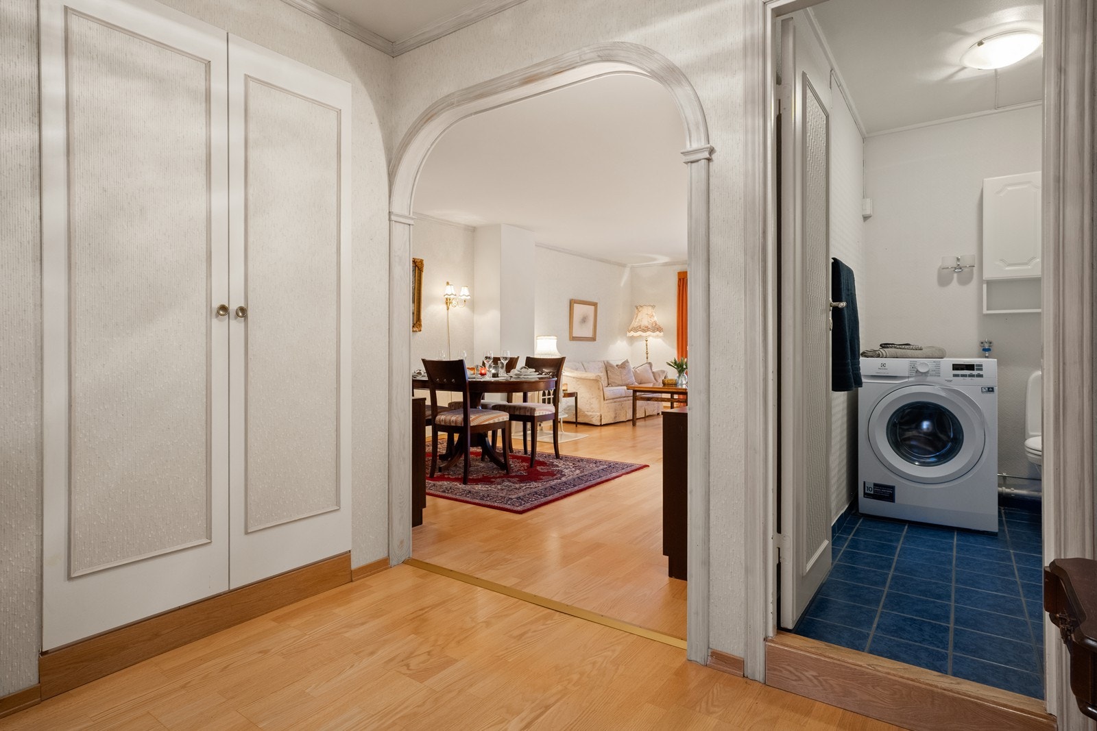 Fra entreen leder en buet åpning deg inn til stuen, med badet praktisk plassert ved siden av. Galleribilde