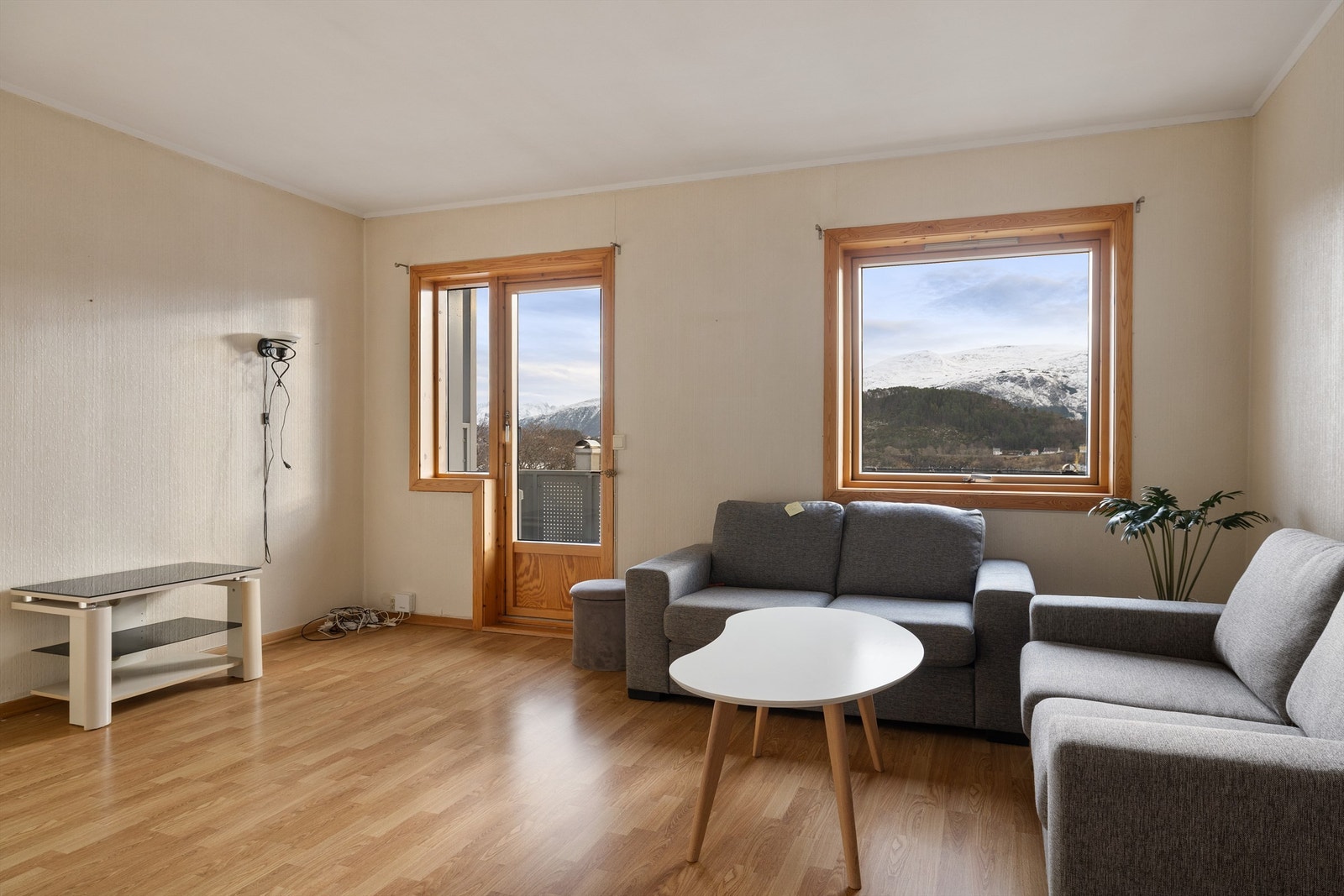 Lys stue med flott utsikt over snødekte fjell og frodig natur Galleribilde