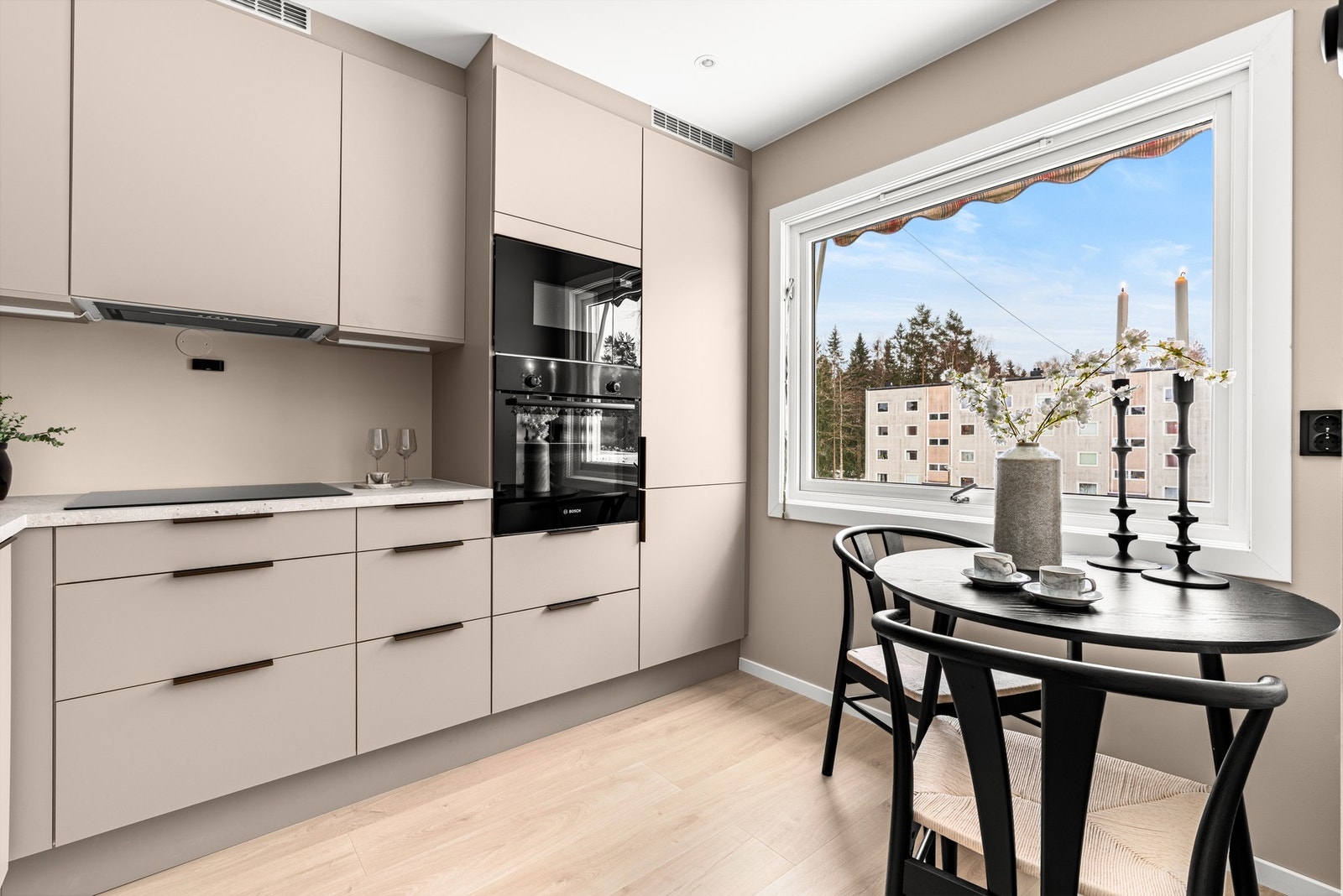 Kjøkkenet har samme enstavs laminatgulv som stuen og lysbeige overflater. Ved vinduet er det fin plass til å innrede med et spisebord. Galleribilde