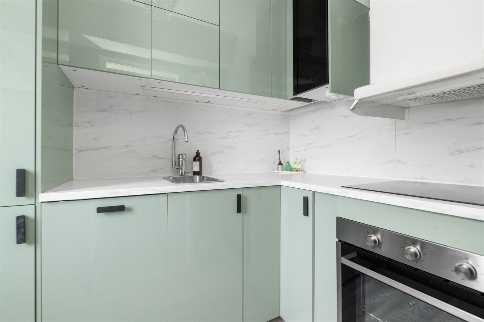 Takhøye overskap gir optimal utnyttelse av plassen, og hjørneskapet er innredet med praktisk rundell. Legg også merke til benkeplatene i kompositt som er videreført opp over benken for å beskytte mot vannsprut og stekefett ved matlaging. Galleribilde