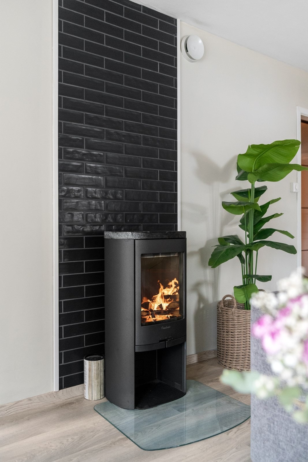 Brannveggen som er bekledd med sort flis gir stua et varmt og moderne uttrykk. Galleribilde