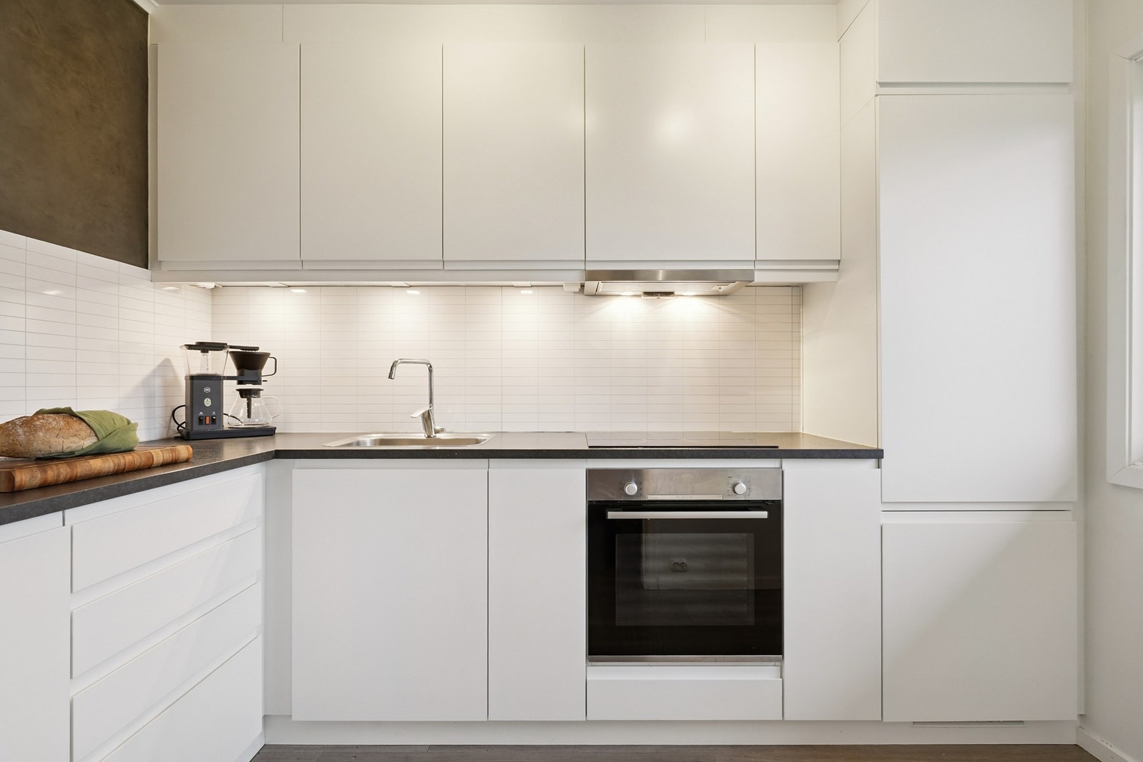 Kjøkkenet har en praktisk utforming. Innredningen har hvite glatte fronter og laminat benkeplate. Galleribilde