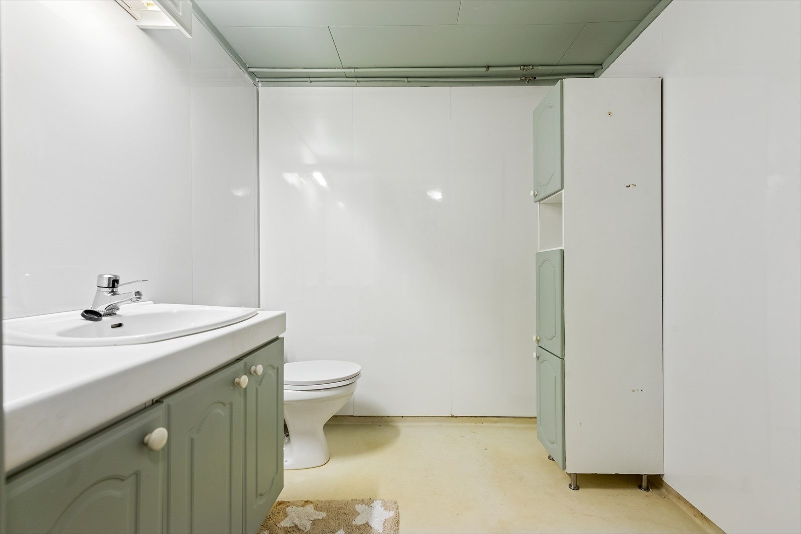 Praktisk toalettrom i kjelleren, utstyrt med gulvmontert toalett og servant. Galleribilde