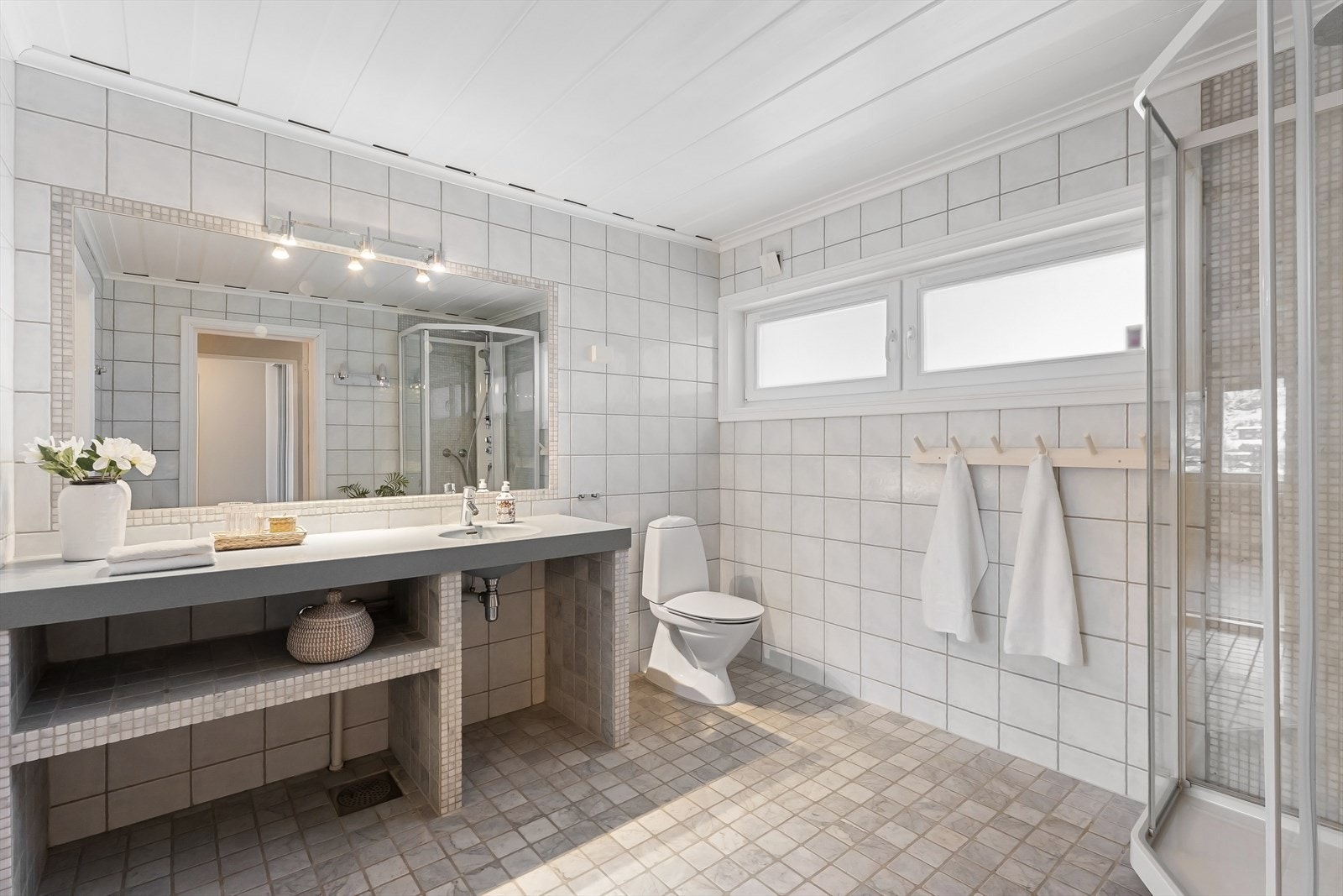 Badet i 1. etasje er flislagt på gulv og vegger med innlagt gulvvarme. Innredningen er fra JKE og baderomsinnredningen er i Corian. Galleribilde