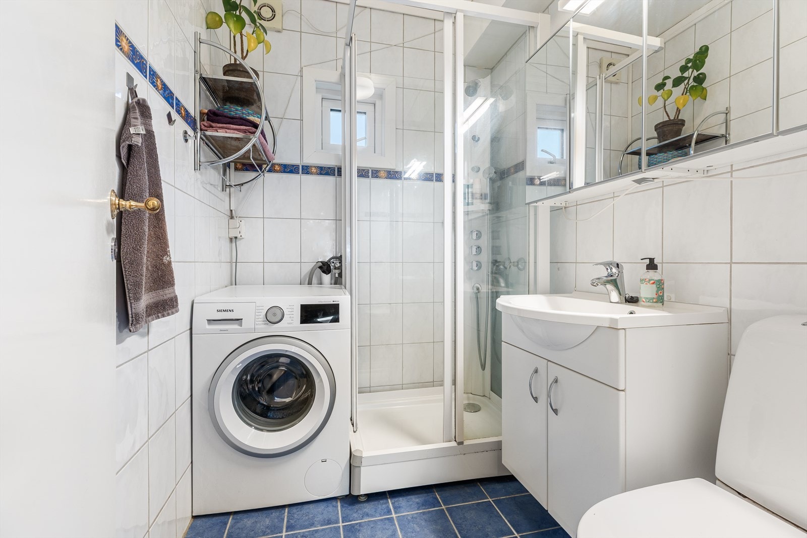 Badet er innredet med nedfelt servant, toalett, dusjkabinett og opplegg for vaskemaskin. Galleribilde