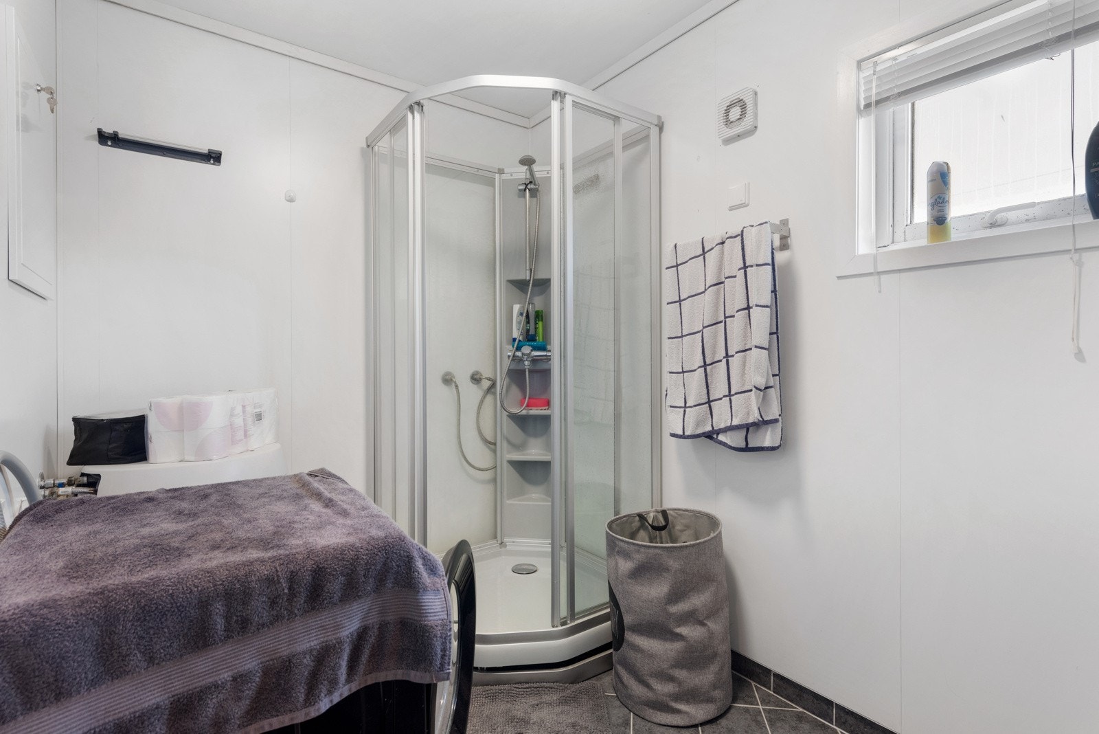 Badet er innredet med servant i innredning med skap, toalett, dusjkabinett og opplegg til vaskemaskin Galleribilde