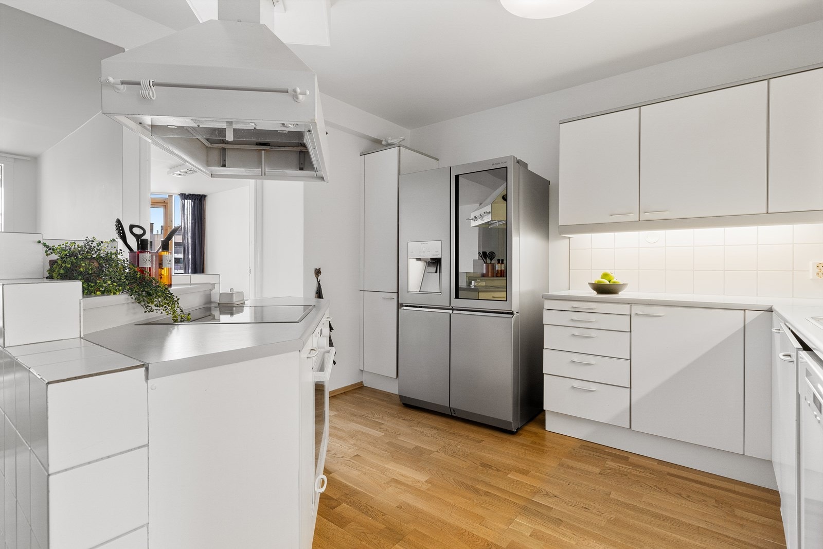 Lys, tidløs innredning med glatte fronter, fliser på vegg over benkeskap og benkeplate i laminat. Galleribilde