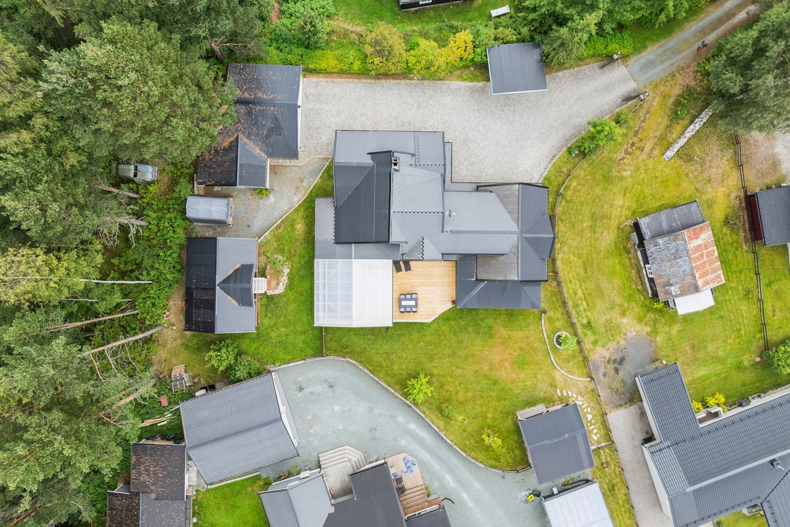 Eiendommen har en flott komposisjon med hovedhus, terrasser og flere garasjebygg Galleribilde