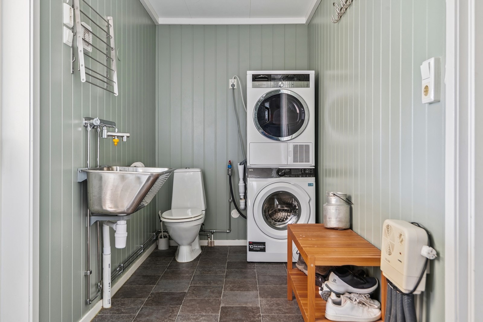 Praktisk vaskerom med toalett, skyllekar og opplegg for vaskemaskin Galleribilde