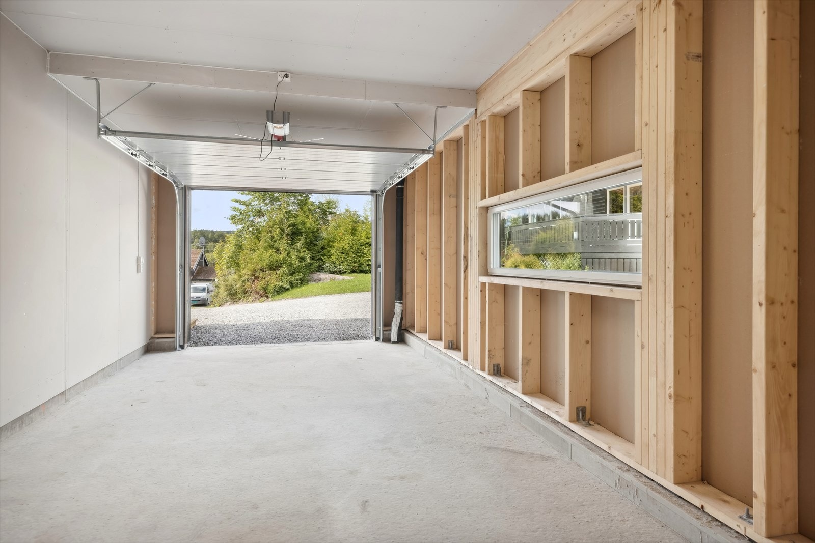 Romslig garasje med motorstyrt leddport. I tillegg er det dør i bakkant av garasjen ut til hagen. Galleribilde