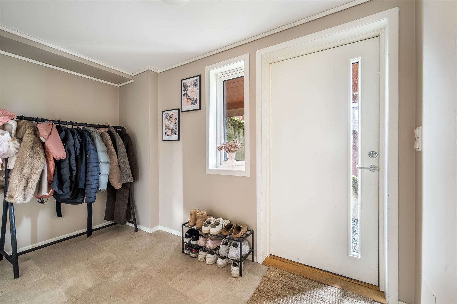 Lys og innbydende entré med fin plass til garderobeløsning. Moderne gulv og nøytrale farger gir et stilrent inntrykk. Galleribilde