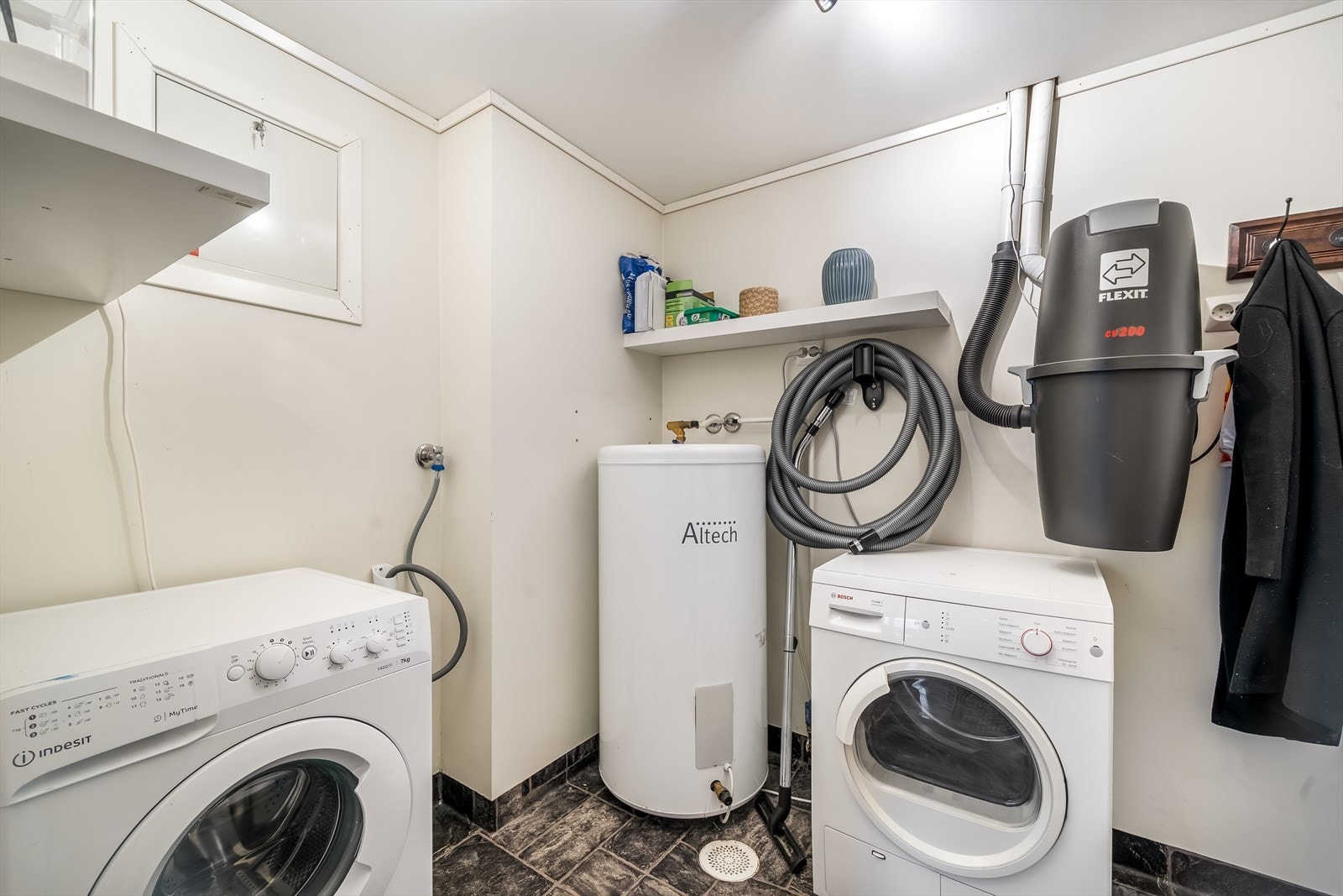 Praktisk vaskerom med vaskemaskin, tørketrommel, varmtvannsbereder og sentralstøvsuger. Galleribilde