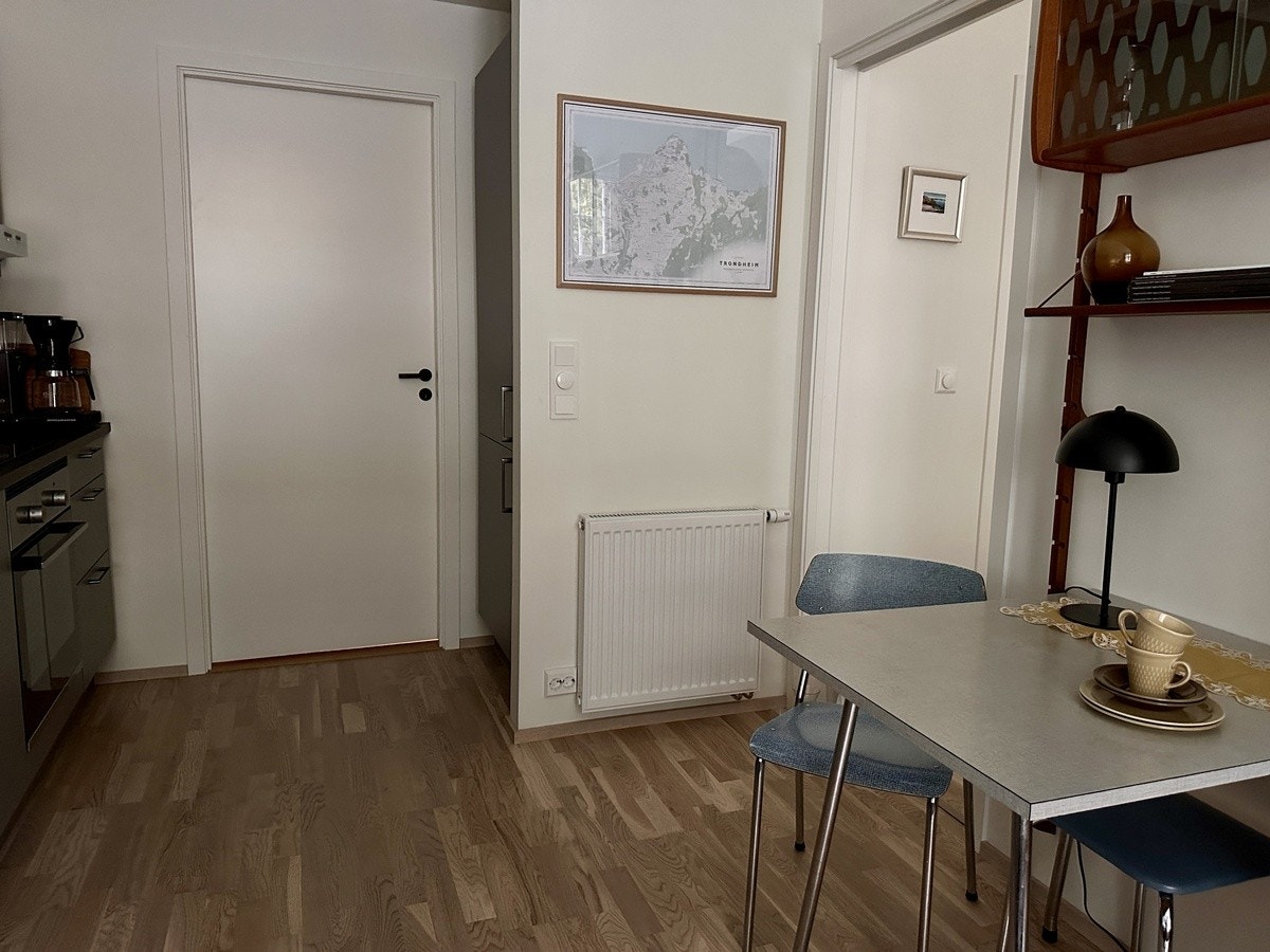 Plass til en liten spiseplass i kjøkken/stue. Kjøl og frys står plassert bak veggen med bilde. Galleribilde