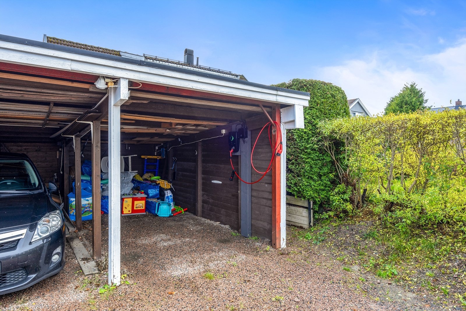 Parkering skjer i carport i felles rekke, hvor elbillader er montert Galleribilde