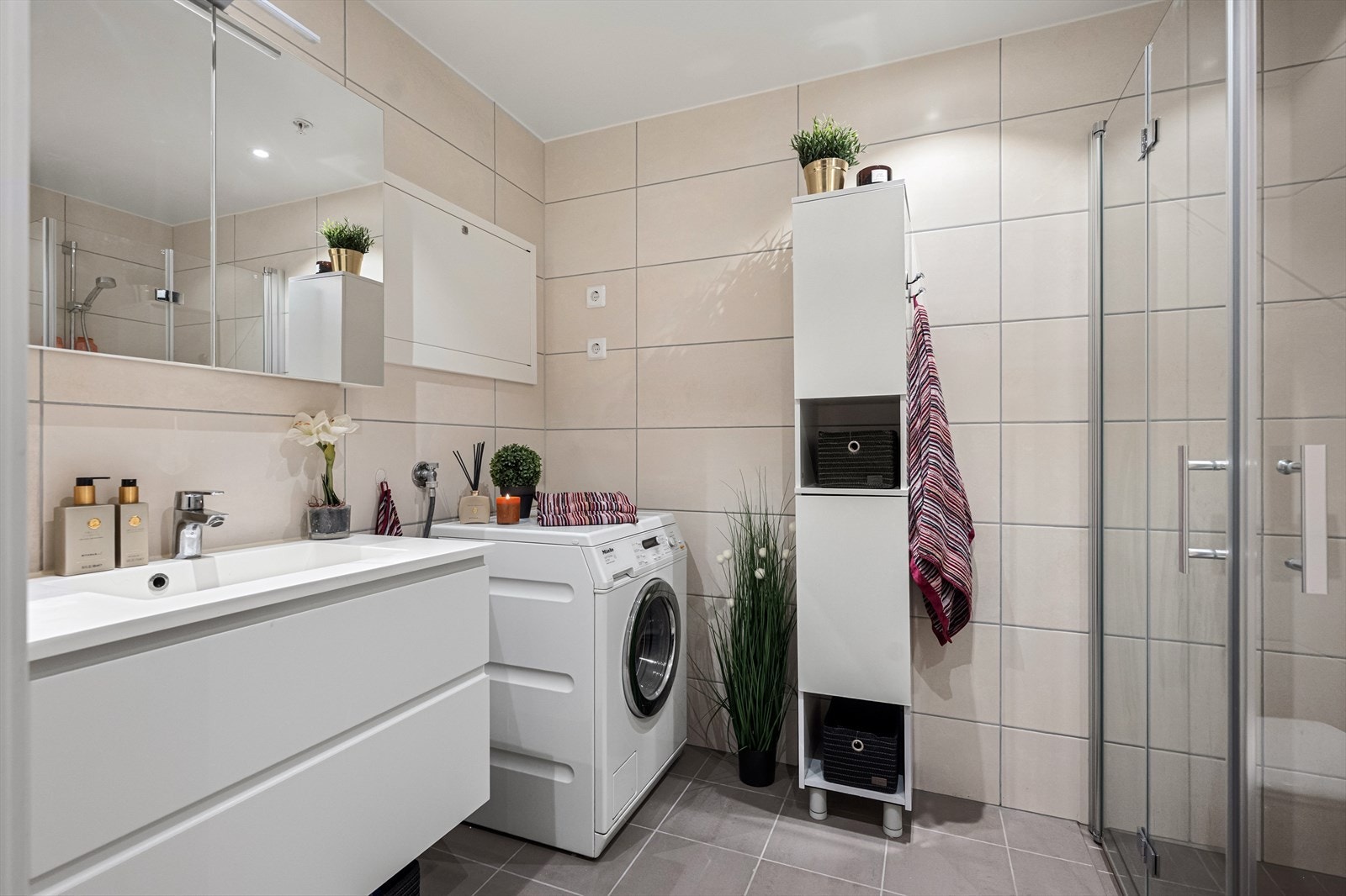 Det ene av leilighetens to bad har flislagte overflater og opplegg for vaskemaskin. Galleribilde