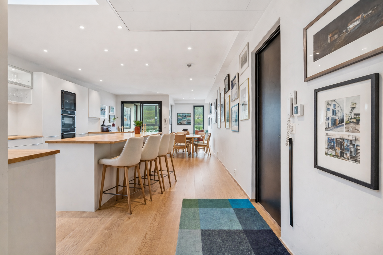 Stilrent og innbydende kjøkken som fungerer som hjemmets naturlige samlingspunkt, med god takhøyde, lyse overflater og flere soner perfekt for både matlaging og hyggelige stunder. Bildet inneholder digital møblering. Galleribilde